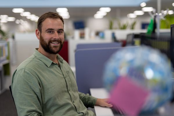 Early career psychologist sits at desk smiling at camera