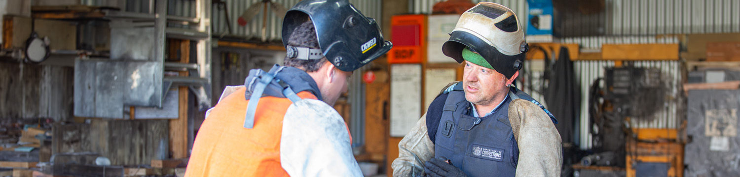Engineering instructor engages with trade participant with workshop in the background