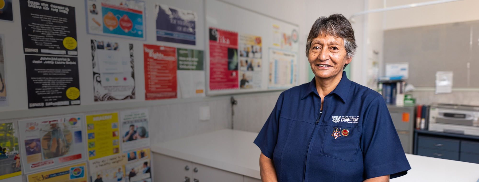 Nurse stands in health centre with posters in the background
