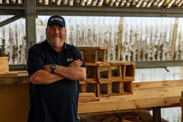 Community Work Supervisor stands with wooden bench behind him and rows of wooden boxes