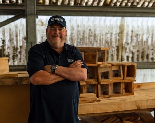 Community Work Supervisor stands behind rows of wooden boxes