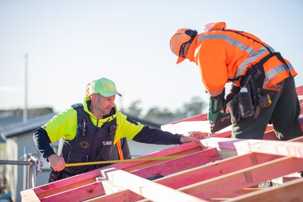 Instructor helps someone with building the roof of a house